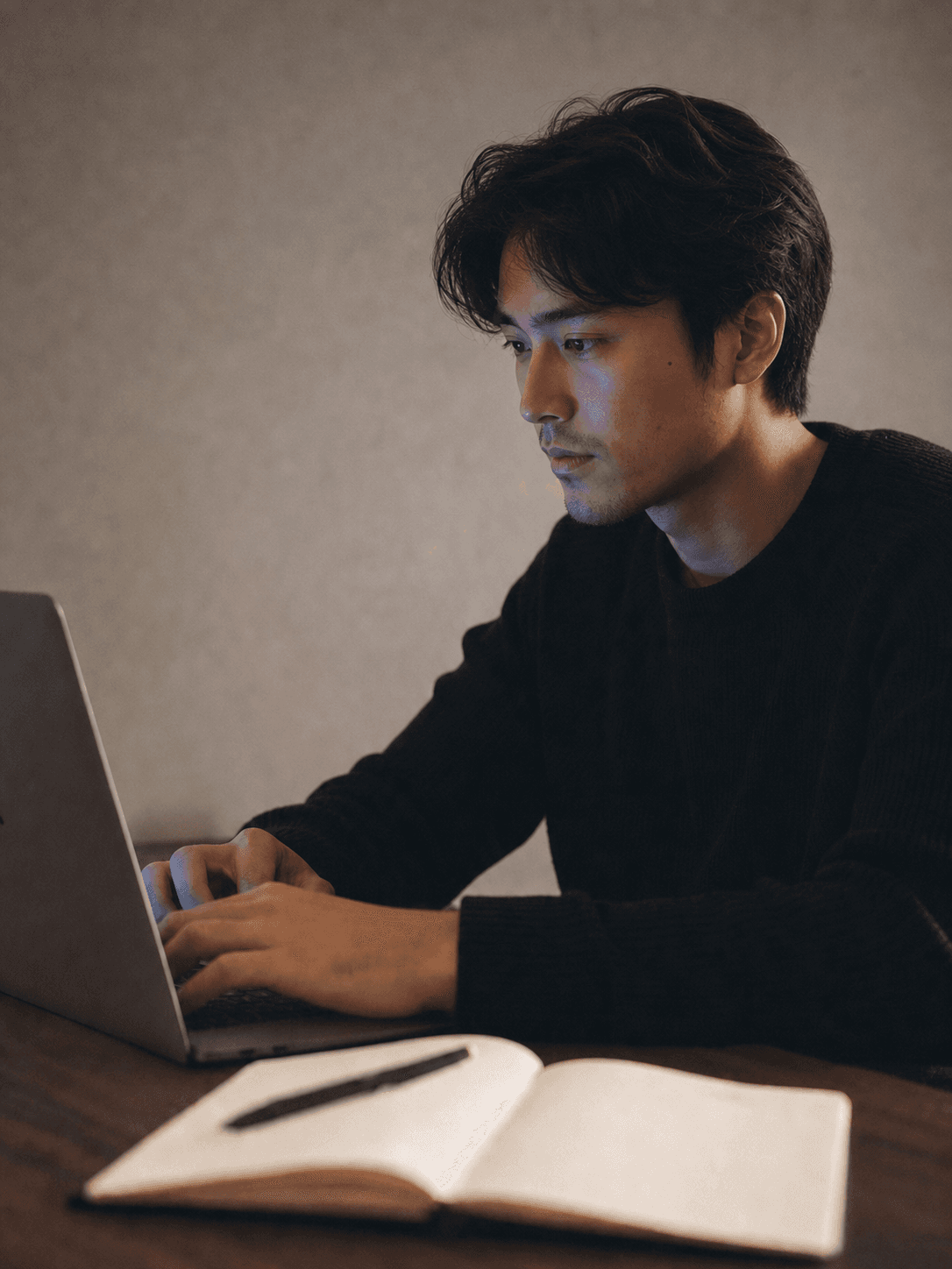 A designer working intently on a laptop, lit by the screen